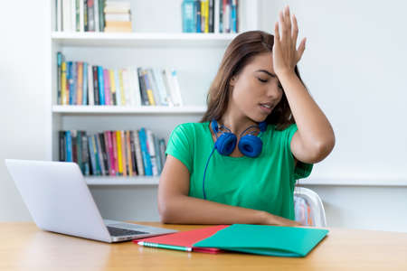 Young colombian female student with problems at desk at homeの写真素材