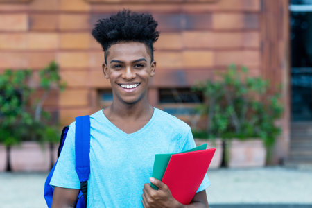 Happy laughing afro american male student with backpack and paperworkの写真素材