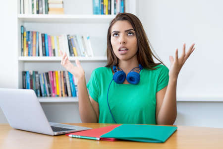 Angry Colombian female student at desk at homeの写真素材