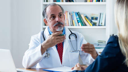 Hispanic male doctor explaining disease to female patient at clinicの写真素材