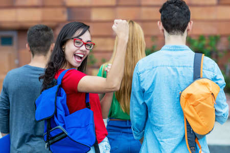 Cheering italian female student with group of other students at campus of universityの写真素材