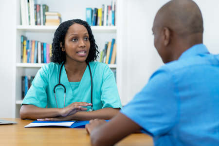 African american female doctor talking with patient about risk of vaccination at hospitalの写真素材