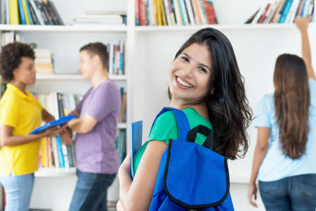 Laughing spanish female student with backpack at classroom of collegeの写真素材