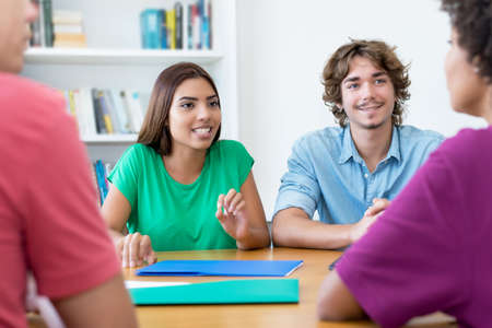 Latin and caucasian male and female students learning for exam at classroom of universityの写真素材