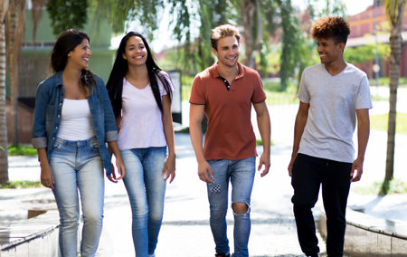 Laughing group of multi ethnic hipster young adults outdoors in city in summerの写真素材