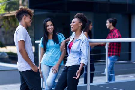 Relaxing latin and hispanic and african american hipster young adults outdoors in city in summerの写真素材