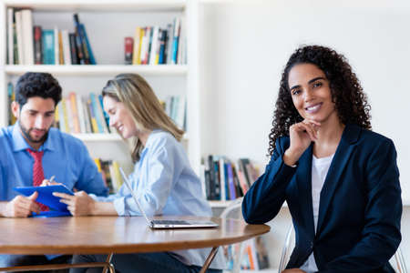 Beautiful young hispanic businesswoman at deskの写真素材