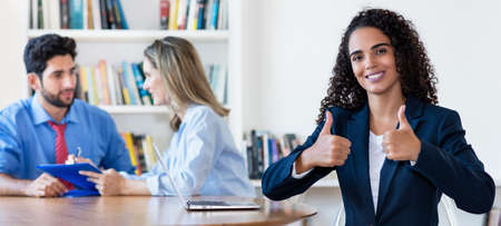 Motivated young hispanic businesswoman showing thumb upの写真素材