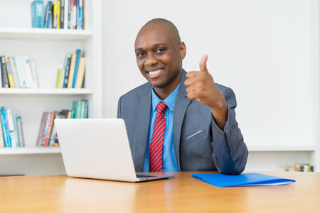 African american businessman at computer showing thumb upの写真素材