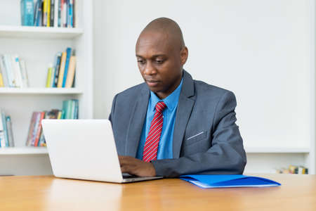 African american businessman working with concentration at computer at desk at officeの写真素材
