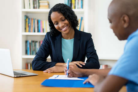 African american man signing contract for insurance at office at office