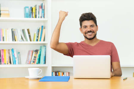 Hispanic mature man with beard shopping online at computerの写真素材