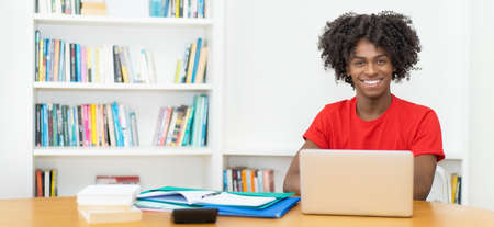 Laughing afro american male student learning and working at computerの写真素材