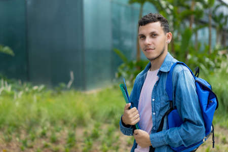 Hispanic male student walking to university at campus of university