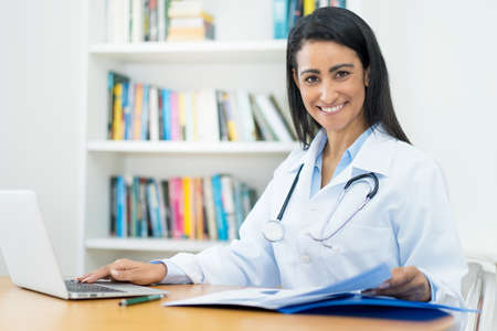 Beautiful latin american female gynecologist at desk at workの写真素材