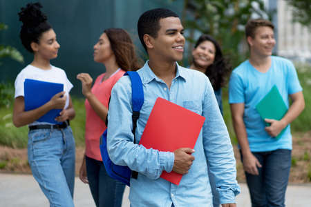 Young brazilian male student with braces and group of multi ethnic young adults outdoor in cityの写真素材