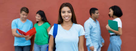 Beautiful mexican female student with group of multiethnic students outdoors in summerの写真素材