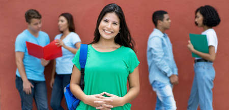 Beautiful caucasian female student with group of multi ethnic young adults outdoor on college campusの写真素材
