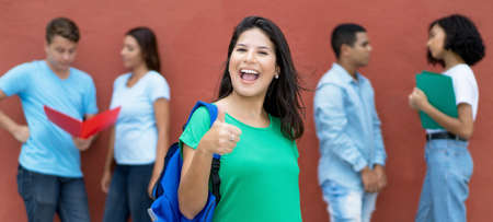 Caucasian female student showing thumb up with group of multi ethnic young adults  on college campusの写真素材