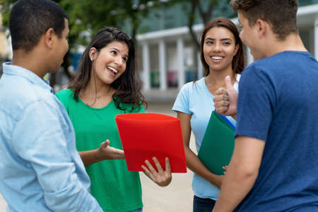 Group of multi ethnic male and female students talking about studies outdoor in cityの写真素材