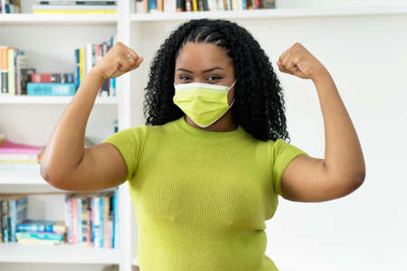 Cheering african american woman with green face maskの写真素材