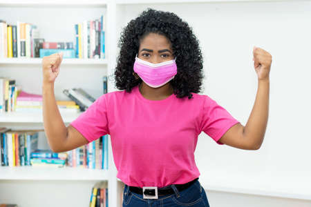 Cheering african american woman with pink face mask