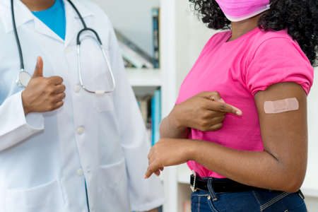 Nurse and african american woman recommending vaccination against Covid-19の写真素材