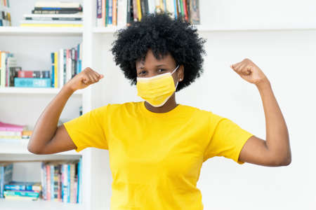 Cheering african american woman with yellow face maskの写真素材