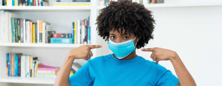 African american woman pointing to blue face maskの写真素材