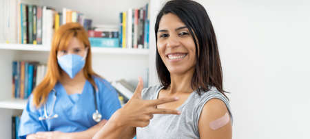 Pretty latin american woman after third vaccination against Covid 19 with nurse vaccination centerの写真素材