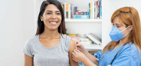 Beautiful latin american woman after third vaccination against Covid 19 with nurse vaccination centerの写真素材