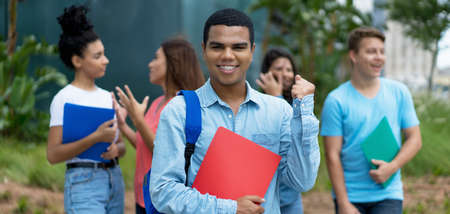 Cheering brazilian male student with braces and group of multi ethnic young adults outdoor in cityの写真素材