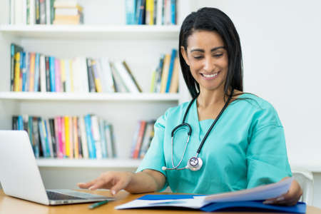 Pretty mexican female nurse at desk at work at hospitalの写真素材