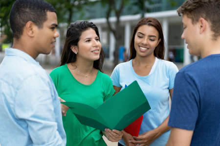 Multi ethnic male and female students in discussion outdoor in city
