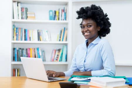 Laughing african american student or business trainee working at computer at desk at officeの写真素材
