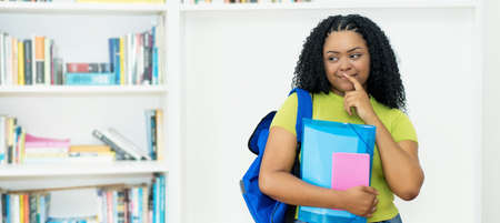 Corpulent african american female student with green shirt in dreams at classroom of universityの写真素材