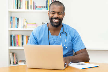 Video call of african american doctor with patient at computer at hospitalの写真素材