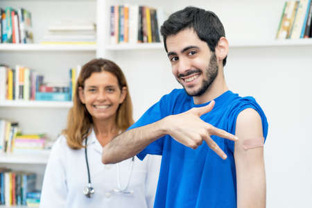 Young arabic man after third vaccination against Covid 19 with nurse at hospitalの写真素材