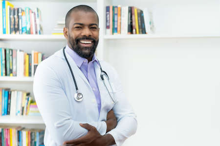 Laughing african american doctor with beard and stethoscope at office of hospitalの写真素材
