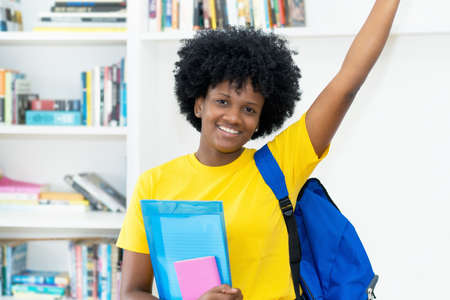 Successful cheering african american female student with yellow shirt at universityの写真素材