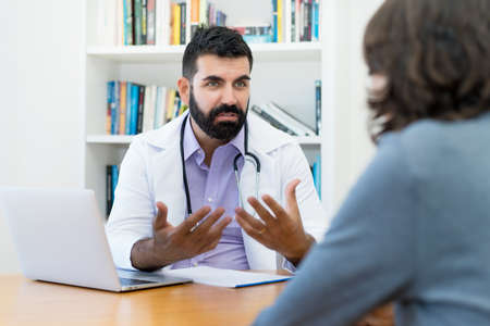 Mature doctor with hipster beard warning patient at office of hospitalの写真素材