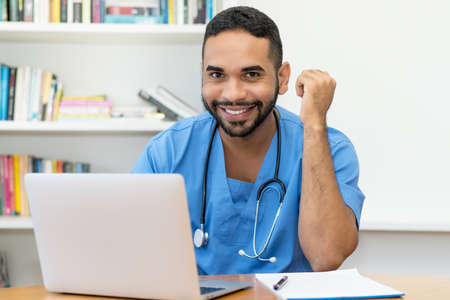 Laughing latin american medical student at computer at hospitalの写真素材