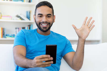 Video call of latin american hipster man with beard indoors at homeの写真素材