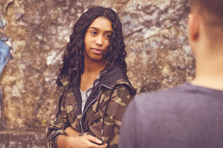 Shy south american hipster woman talking with boyfriend outdoor in urban styleの写真素材