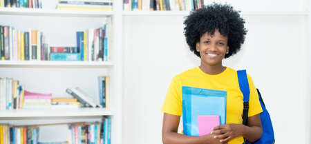 Pretty african american female student with yellow shirt at universityの写真素材