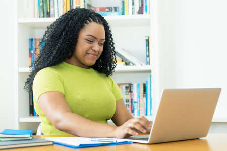 Corpulent african american female student learning at computer indoors at homeの写真素材