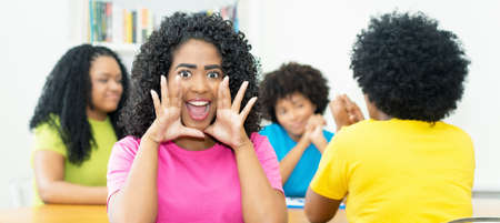 Happy brazilian female student with group of african american young adults at classroom of collegeの写真素材