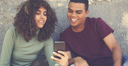 Latin american young adult couple shopping online at mobile phone outdoor in urban city styleの写真素材