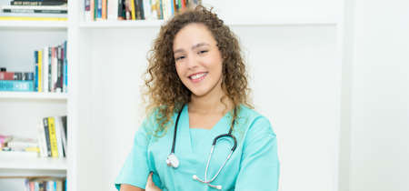 Laughing caucasian female nurse or medical student with curly hair at hospitalの写真素材