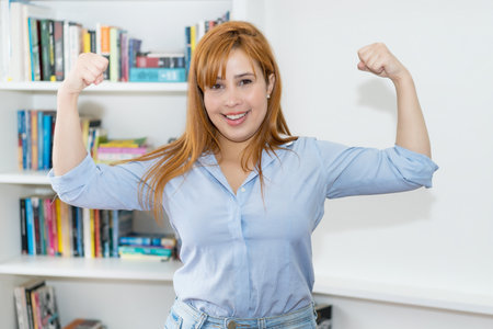 Successful cheering woman with red hair indoors at homeの写真素材